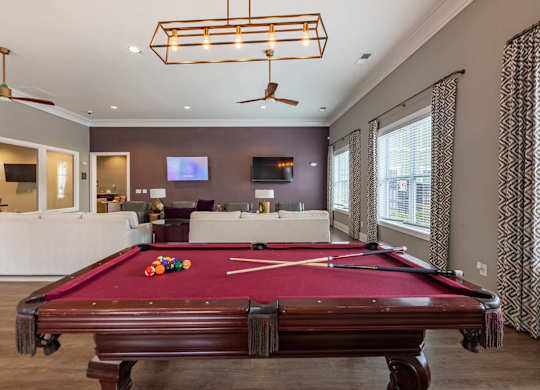 A pool table is in the middle of a room with a television and a fan at Foxwood Apartments, Raleigh-Durham