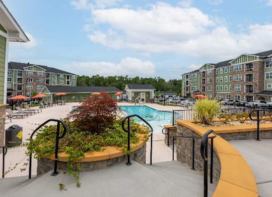 A pool area with a small tree in a planter and a wall of apartment buildings in the background at Foxwood Apartments, Raleigh-Durham, NC, 27616