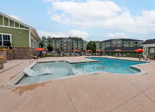 A large outdoor swimming pool surrounded by a patio and umbrellas at Foxwood Apartments, Raleigh-Durham, 27616