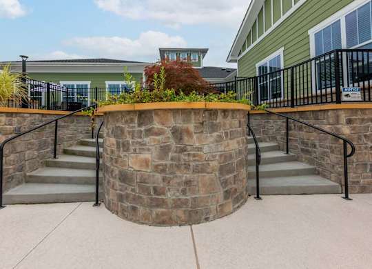 A stone wall with metal railings and steps leading up to a building at Foxwood Apartments, Raleigh-Durham, NC