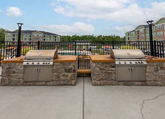 Two stone BBQs are in front of a black fence at Foxwood Apartments, Raleigh-Durham, North Carolina