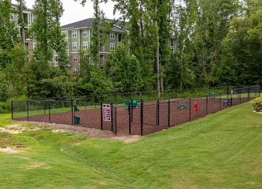 A green lawn with a fence and a sign at Foxwood Apartments, Raleigh-Durham, 27616