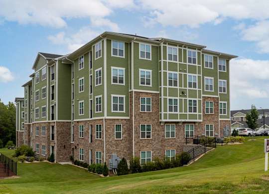 A large apartment building with a green and brown exterior at Foxwood Apartments, Raleigh-Durham, NC, 27616