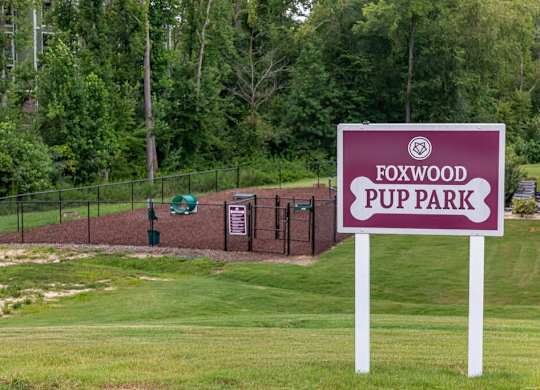 A sign for Foxwood Puppark stands in front of a fenced area at Foxwood Apartments, Raleigh-Durham, 27616
