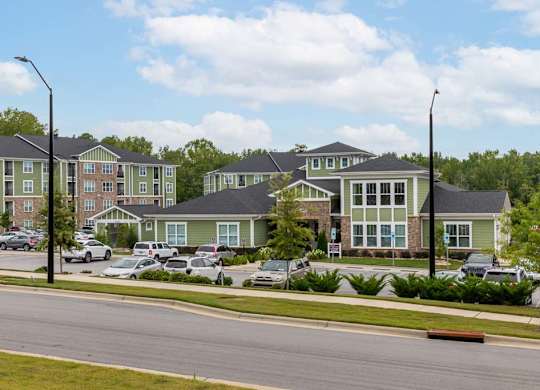 Apartment complex with green and brown buildings and cars parked in front at Foxwood Apartments, Raleigh-Durham, North Carolina