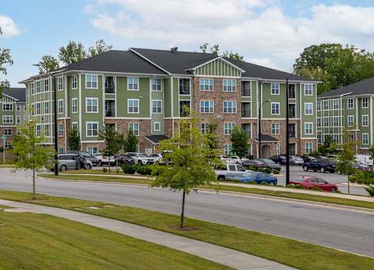 A green and beige apartment building with a parking lot in front at Foxwood Apartments, Raleigh-Durham, North Carolina