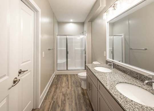 A bathroom with a toilet, sink, mirror, and shower at Foxwood Apartments, Raleigh-Durham, NC