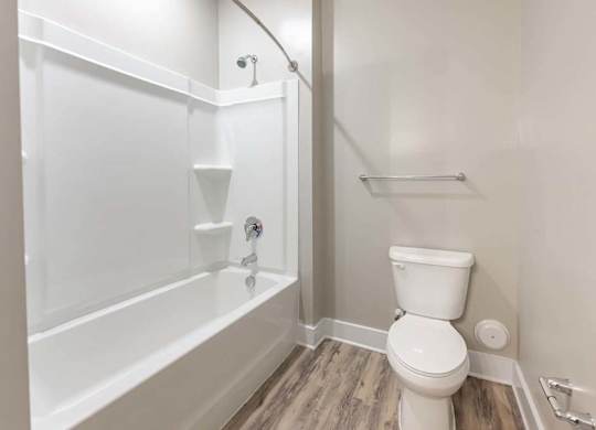 A white toilet sits next to a bathtub in a bathroom at Foxwood Apartments, North Carolina, 27616