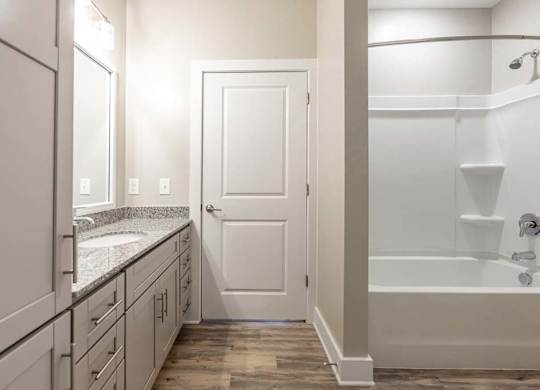 A white bathroom with a tub, sink, and mirror at Foxwood Apartments, Raleigh-Durham, NC, 27616