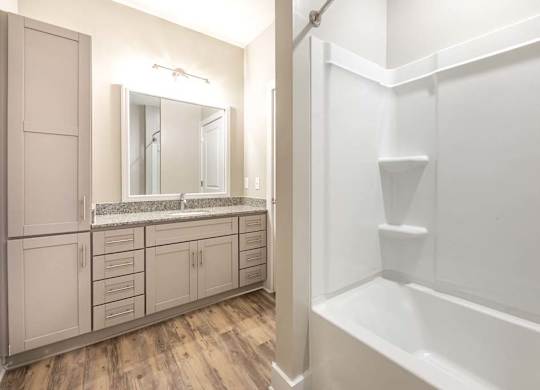 A white bathroom with a wooden floor and a white bathtub at Foxwood Apartments, Raleigh-Durham, NC
