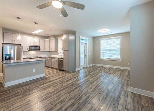 A modern kitchen with a wooden floor and a ceiling fan at Foxwood Apartments, Raleigh-Durham