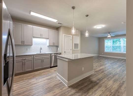 A kitchen with a refrigerator on the left and a counter with a sink at Foxwood Apartments, Raleigh-Durham, NC