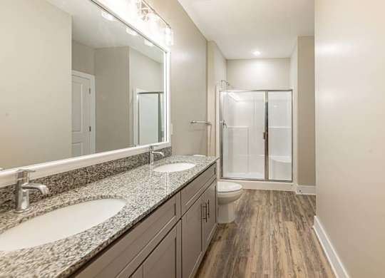 A bathroom with a sink, mirror, and shower at Foxwood Apartments, Raleigh-Durham