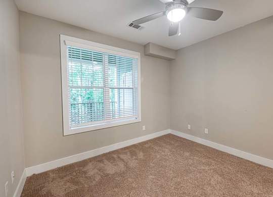 A room with a ceiling fan and a window with blinds at Foxwood Apartments, Raleigh-Durham, North Carolina