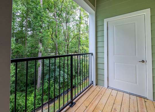 A white door is on the right side of a balcony with a black railing at Foxwood Apartments, Raleigh-Durham, NC