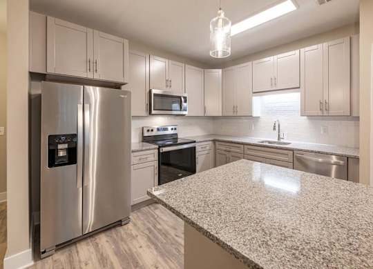 A kitchen with a granite countertop and stainless steel appliances at Foxwood Apartments, North Carolina