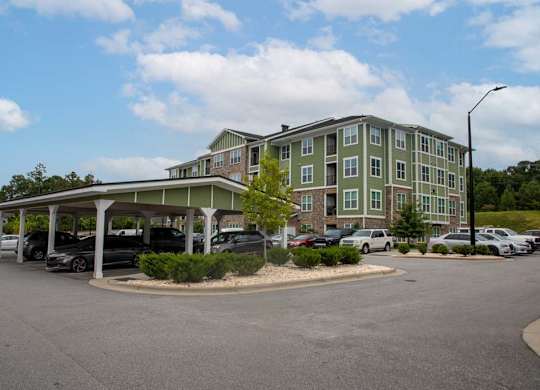 A parking lot in front of a green building at Foxwood Apartments, Raleigh-Durham, NC, 27616