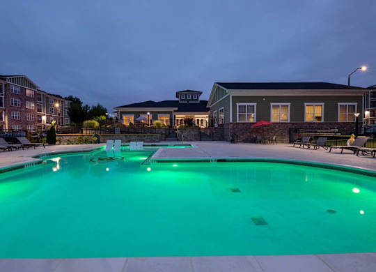 A swimming pool lit up with green lights at dusk at Foxwood Apartments, Raleigh-Durham