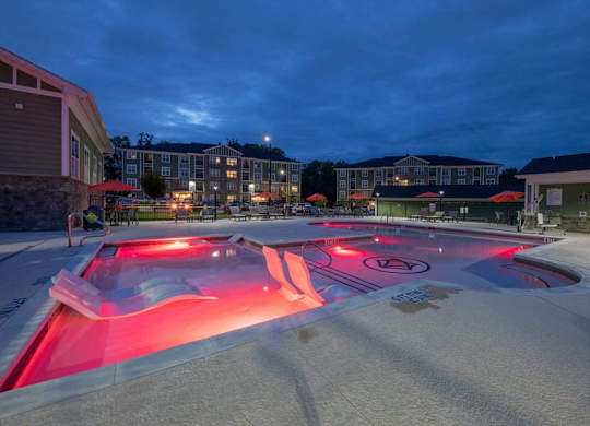 A pool lit up with red lights at night at Foxwood Apartments, North Carolina, 27616