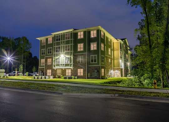 A large building with a greenish hue is illuminated at night at Foxwood Apartments, Raleigh-Durham, North Carolina