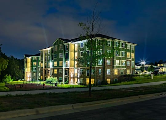 A large green building with lights on at night. at Foxwood Apartments, Raleigh-Durham, 27616