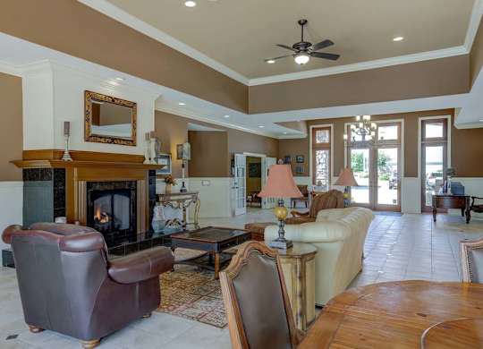 A living room with a brown fireplace and a brown leather chair at Ethan Pointe Apartments, Greensboro, North Carolina