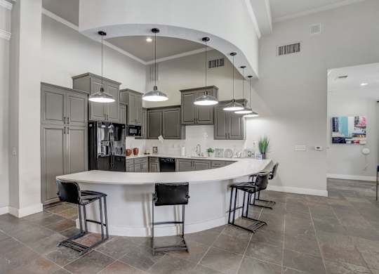 A modern kitchen with a curved island and bar stools.