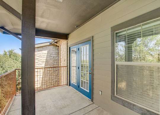 A balcony with a blue door and a window.