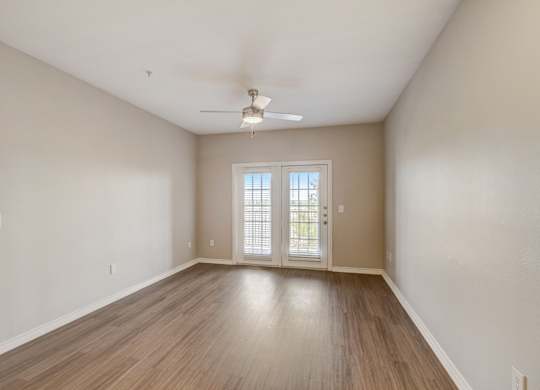 A room with a sliding glass door and a ceiling fan.