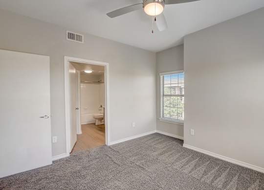 A room with a ceiling fan and carpeted floor.