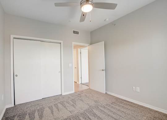 A room with a ceiling fan and carpeted floor.