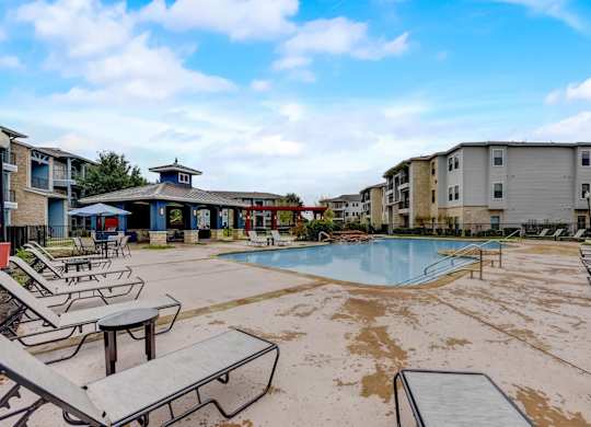 A pool area with sun loungers and a small building in the background.