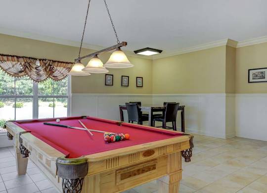 A pool table with a red cloth and a pool cue on it at Ethan Pointe Apartments, Greensboro