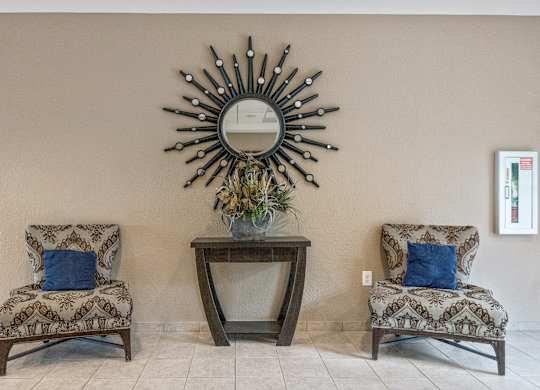 Two chairs and a table with a mirror above it.