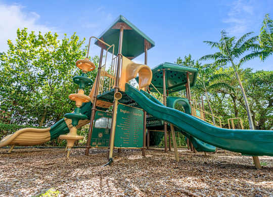 A playground with a green slide and a wooden structure.