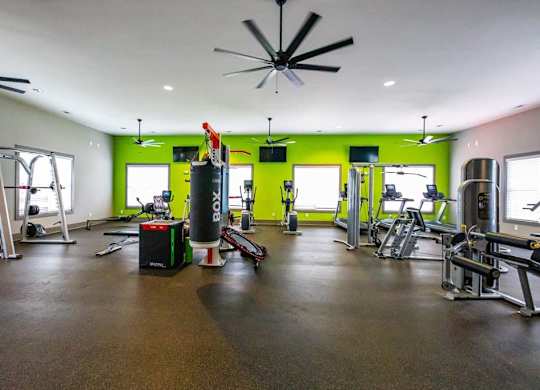 A gym with a green wall and a black ceiling fan. at Foxwood Apartments, North Carolina
