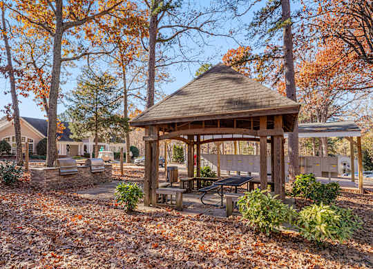 A gazebo surrounded by trees with orange leaves.