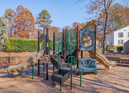 A playground with a slide, a climbing frame and a table.