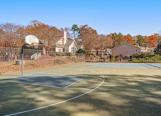 A basketball court with a basketball hoop and a chain link fence.