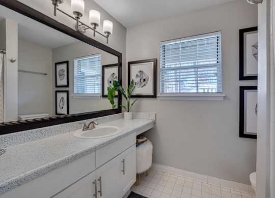 A bathroom with a sink, mirror, and tiled floor.