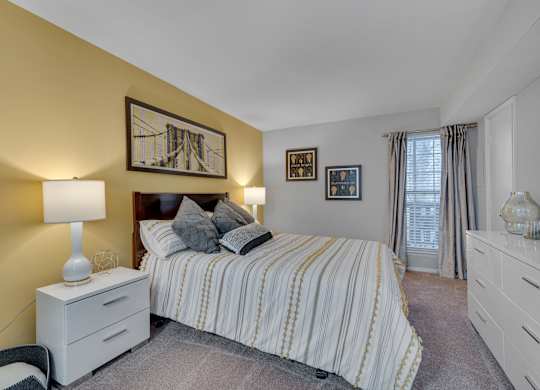 A bedroom with a bed, nightstand, and a painting on the wall.