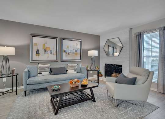 A living room with a grey couch, a white armchair, a coffee table, and two framed pictures on the wall.