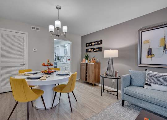 A dining room with a white table and yellow chairs.
