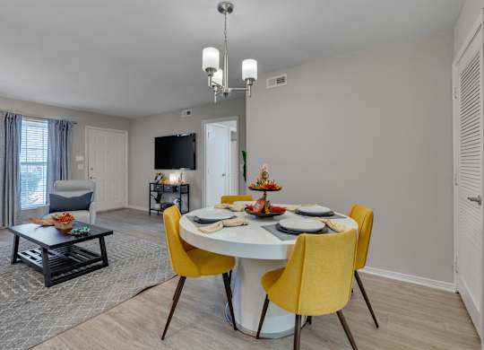 A dining room with a white table and yellow chairs.