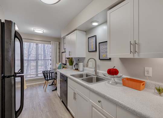 A kitchen with white cabinets and a black refrigerator.