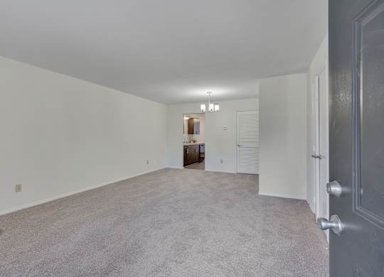 A large, empty room with a carpeted floor and white walls.