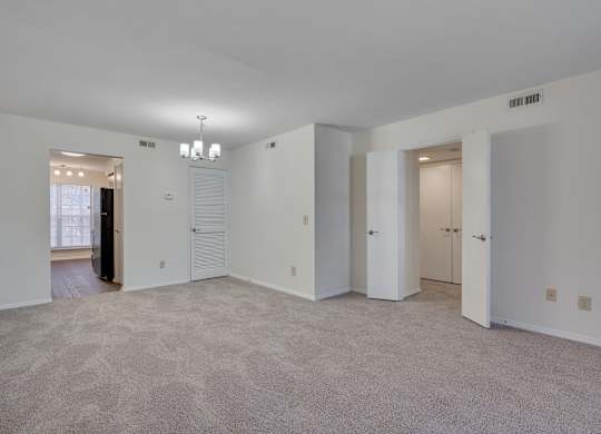 A large empty room with carpeted floor and white walls.