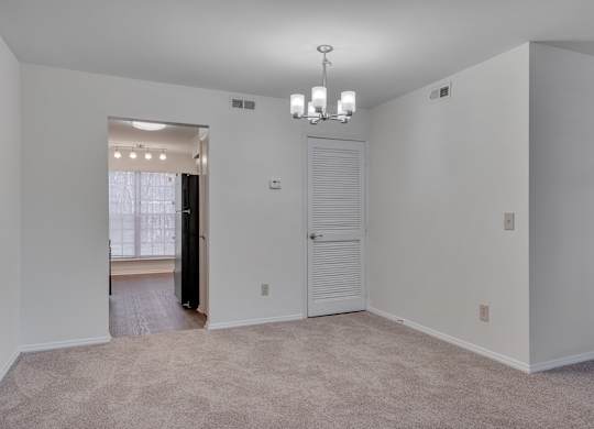 A large, empty room with a carpeted floor and a chandelier hanging from the ceiling.