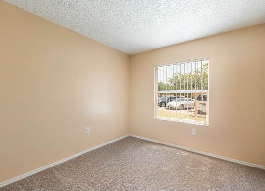 A room with a window showing a parking lot outside.