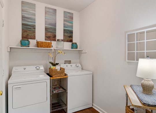 Laundry Room with a white washer and dryer, wood shelving and hardwood style floors.